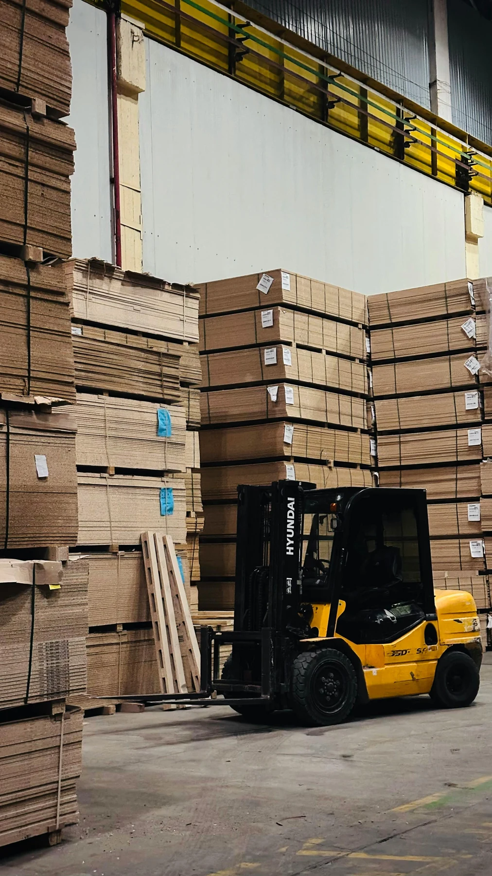 Forklift handling corrugated board stacks inside the facility